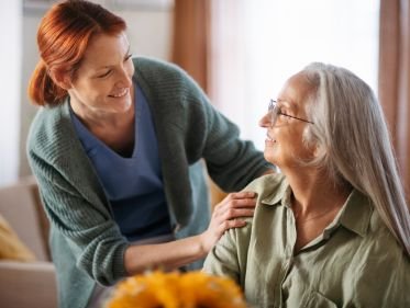 Caregiver assisting senior with blood pressure monitoring and medication organization at home